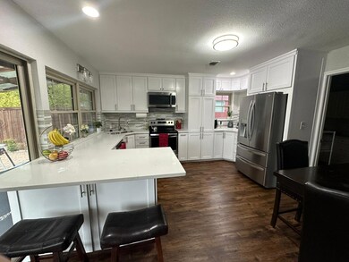 Kitchen featuring dark wood-type flooring, kitchen peninsula, stainless steel appliances, a kitchen bar, and tasteful backsplash