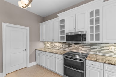 Kitchen featuring appliances with stainless steel finishes, glass insert cabinets, and dark stone countertops