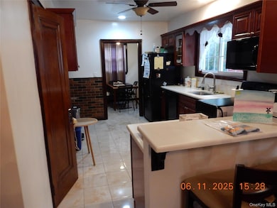 Kitchen featuring glass insert cabinets, light countertops, black microwave, ceiling fan, and light tile patterned floors