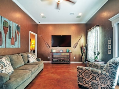 Living room featuring ceiling fan, ornamental mold