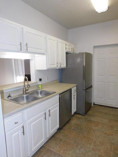 Kitchen featuring white cabinetry, light countertops, and dishwasher