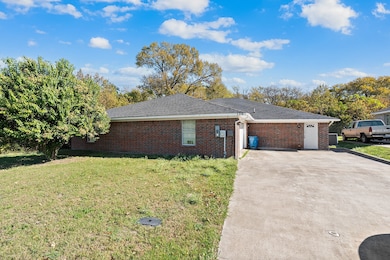 View of side of property featuring a yard, concrete driveway, brick siding, and a shingled roof