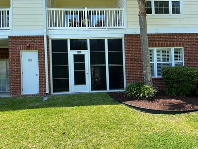 Doorway to property featuring a balcony, a yard, and brick siding
