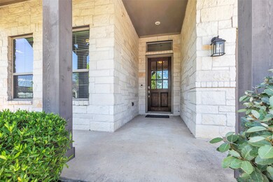 Welcoming front porch with a covered entryway, sto