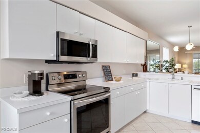 Kitchen with stainless steel appliances, white cabinets, light countertops, and light tile patterned floors