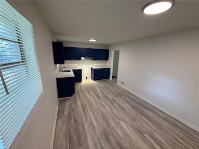 Kitchen with blue cabinets, light countertops, and dark wood finished floors