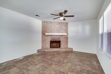 Unfurnished living room featuring a brick fireplace, a ceiling fan, a textured ceiling, and stone finish floors