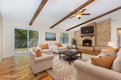 Virtually staged-
Living area with light wood-type flooring, a brick fireplace, and ceiling fan
