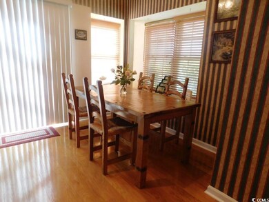 Dining room with wallpapered walls and light wood-