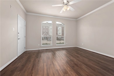 Spare room featuring crown molding, dark wood-style floors, and ceiling fan