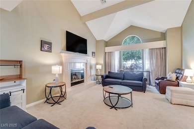 Living room with high vaulted ceiling, light carpet, and a tiled fireplace