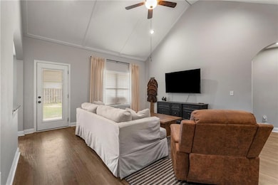 Living room featuring arched walkways, a ceiling fan, wood finished floors, and high vaulted ceiling