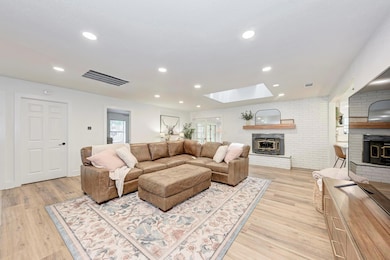 Living room with a brick fireplace, a skylight, l