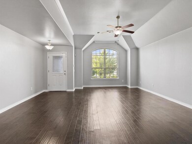 Unfurnished living room featuring a ceiling fan, dark wood-style flooring, and vaulted ceiling
