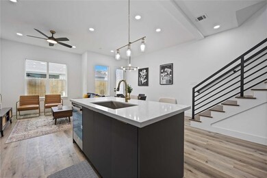The island is open to the living and dining areas and features sleek light fixtures and quartz countertops. Gorgeous floors adorn this sleek living space.