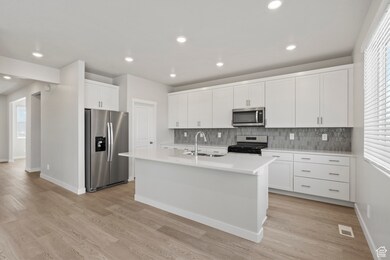 Kitchen with a sink, decorative backsplash, stainless steel appliances, and visible vents