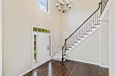 Foyer entrance featuring plenty of natural light, a chandelier, stairway, baseboards, and a towering ceiling