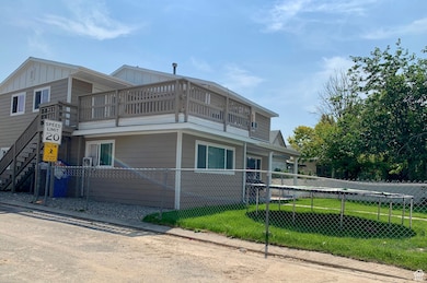 View of side of property featuring a balcony, a fenced front yard, and board and batten siding