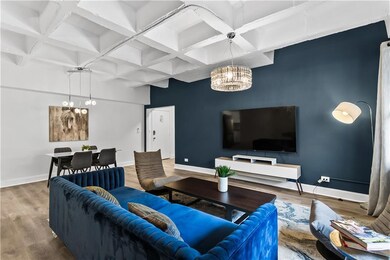 Living area featuring a chandelier, coffered ceiling, wood finished floors, and beamed ceiling