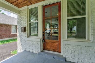 View of exterior entry featuring brick siding and a porch