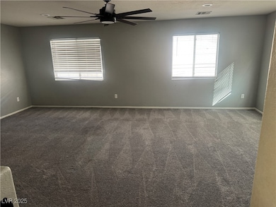 Spare room featuring dark colored carpet, a textured ceiling, and ceiling fan