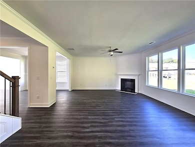 Unfurnished living room featuring plenty of natural light, dark wood-style floors, ornamental molding, and a fireplace