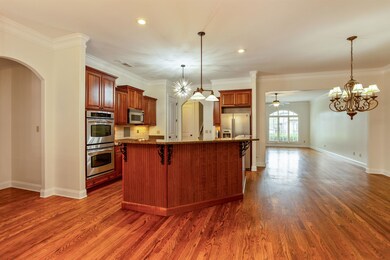 Kitchen featuring stainless steel appliances, dark stone counters, dark wood-style floors, a kitchen breakfast bar, and recessed lighting
