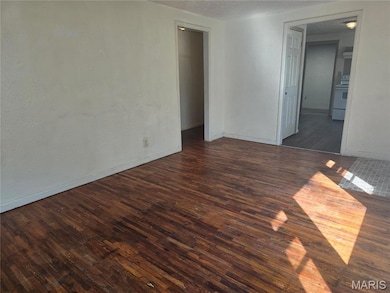 Empty room featuring dark wood finished floors and a textured ceiling