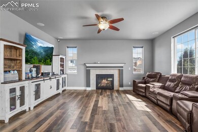 Living room featuring dark wood-type flooring, a tiled fireplace, and a ceiling fan