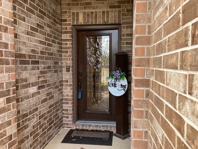 COVERED FRONT PORCH FEATURES A CUSTOM LEAD GLASS DOOR