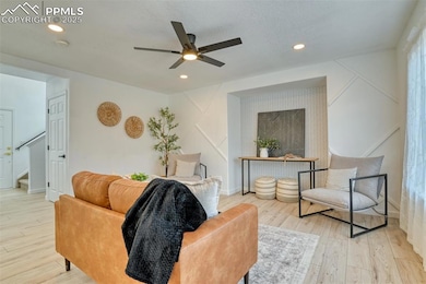 Living room featuring light wood-type flooring, recessed lighting, ceiling fan, and stairs