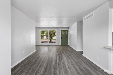 Unfurnished living room with dark wood-style flooring and a textured ceiling