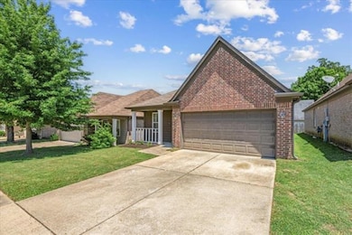 View of front of house with brick siding, a front yard, a garage, and concrete driveway