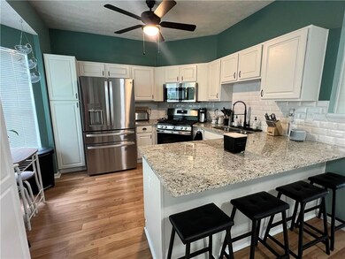 Kitchen with appliances with stainless steel finishes, a peninsula, a sink, light stone countertops, and decorative backsplash