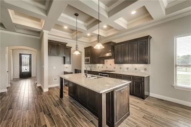 Kitchen featuring tasteful backsplash, stainless steel appliances, a sink, arched walkways, and wall chimney exhaust hood