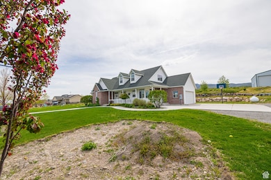 Cape cod house featuring a porch, a front lawn, a garage, brick siding, and driveway