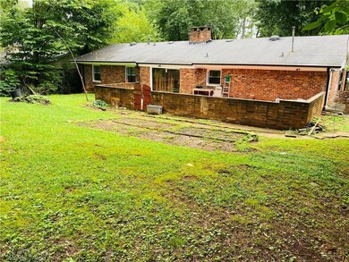 Rear view of property featuring a lawn, a chimney,