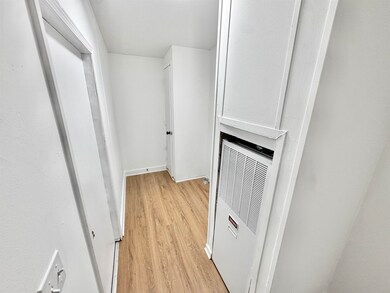 Laundry with a heating unit, light wood-type flooring, and baseboards
