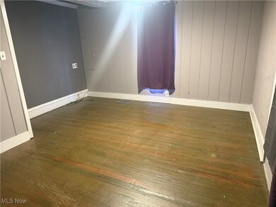 Unfurnished room with dark wood-style flooring and baseboards