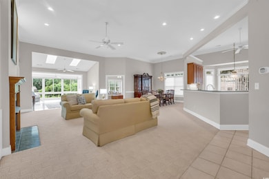 Living area featuring a ceiling fan, a skylight, recessed lighting, ornamental molding, and light tile patterned floors