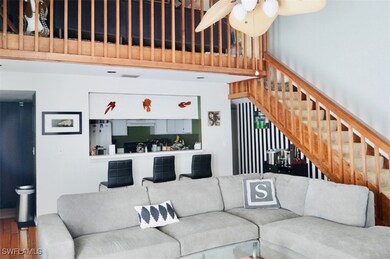 Living area with a ceiling fan, stairs, and wood f