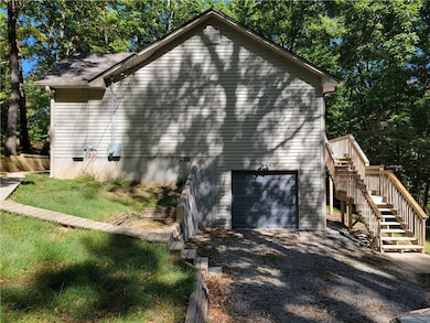View of property exterior with an attached garage, stairs, driveway, and view of scattered trees