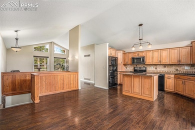 Kitchen with vaulted ceiling, dark wood-style flooring, a textured ceiling, black appliances, and a center island