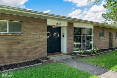 Doorway to property with brick siding and a yard
