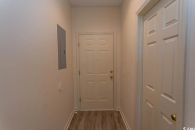 Hallway with electric panel, baseboards, and wood 