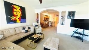 Carpeted living area featuring arched walkways and