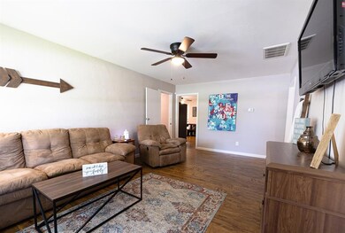 Living area featuring a ceiling fan and dark wood-style flooring