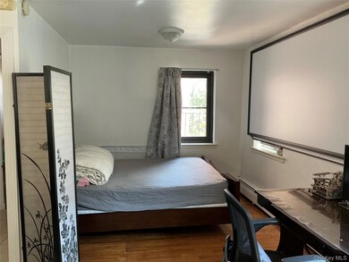 Bedroom with wood finished floors and an office area