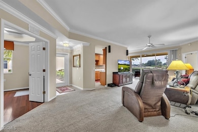 Living room with crown molding, carpet, and a ceiling fan