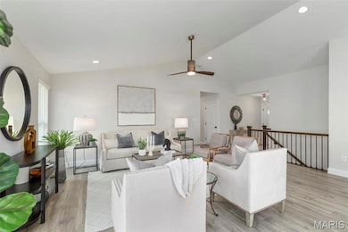 Living room with ceiling fan, light wood-type flooring, and vaulted ceiling